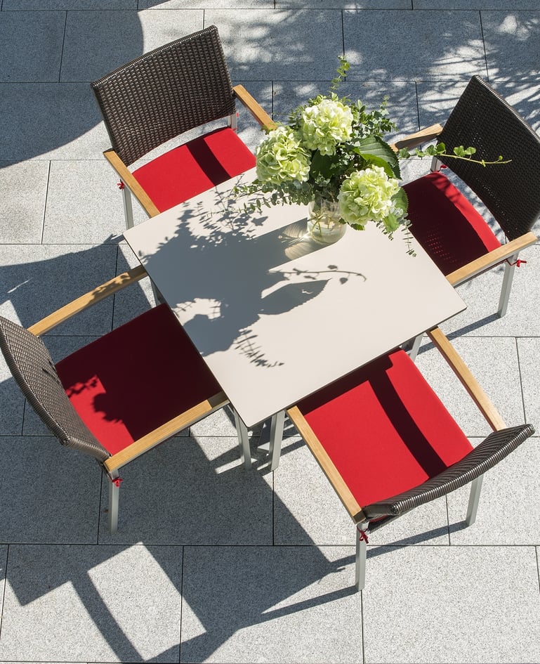 Aufsicht auf Tisch mit vier passenden Stühlen auf sonniger Terrasse