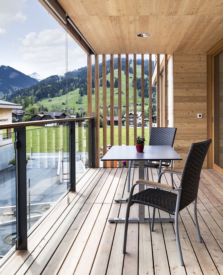 Tisch mit zwei passenden Stühlen auf einem Balkon mit Blick in die Bergwelt