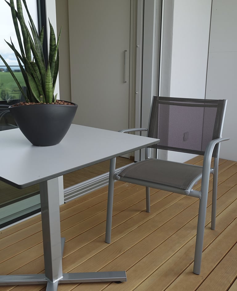 Tisch mit Sukkulente und passendem Stuhl auf einem Balkon