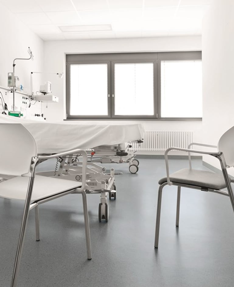 Zwei stapelbare Besucherstühle neben einem Spitalbett